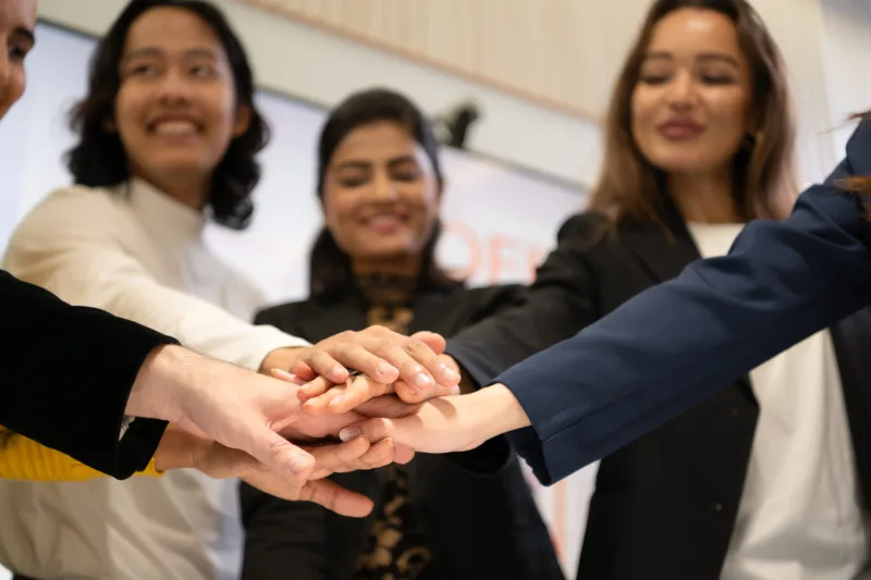 Business people putting their hands together as a symbol of unity and teamwork<br />
